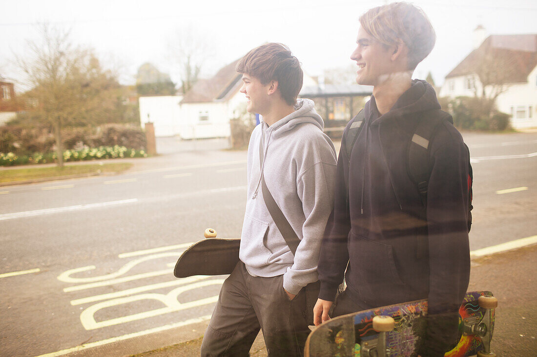 Teenage boys with skateboards walking on sidewalk