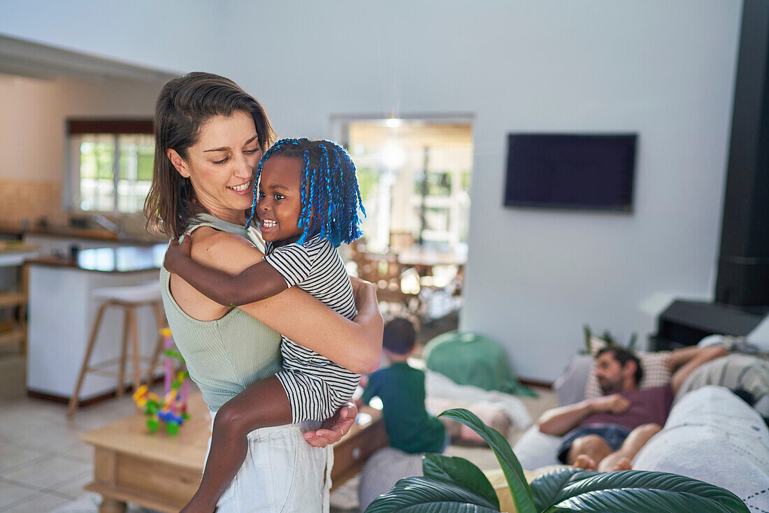 Mother holding cute toddler daughter at home