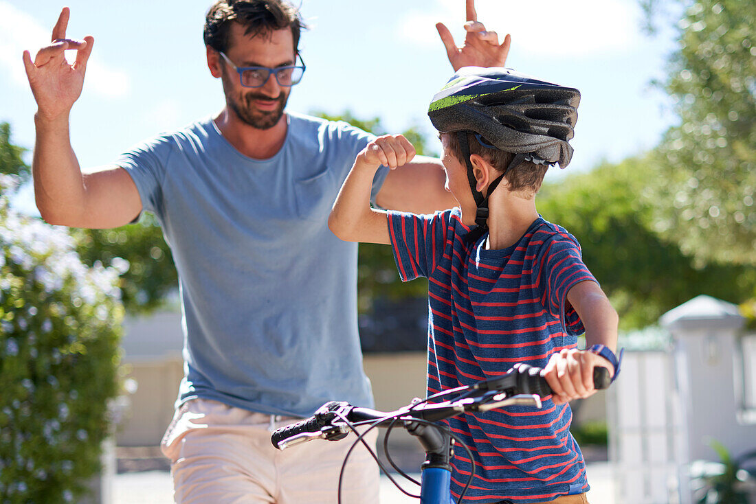 Happy father and son on bike in sunny driveway