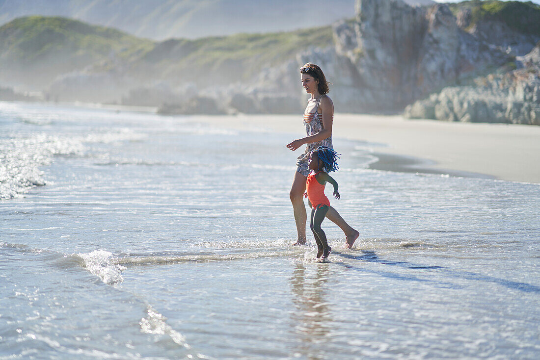Mother and toddler daughter playing in ocean surf