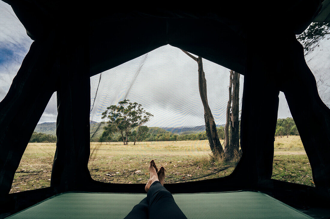 Woman relaxing inside tent in remote Australian bush