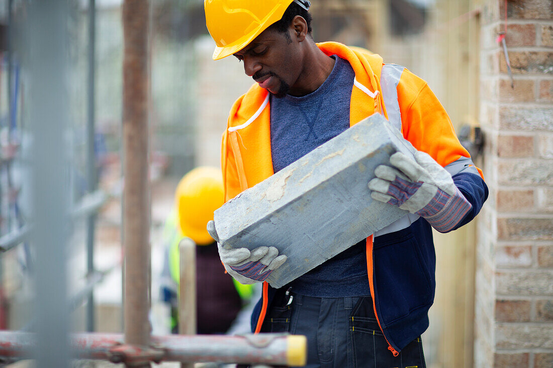 Construction worker carrying brick at construction site