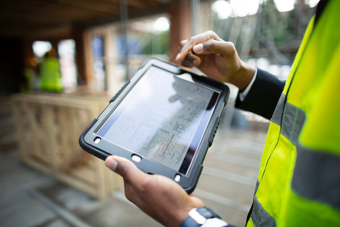 Architect looking at blueprints on digital tablet