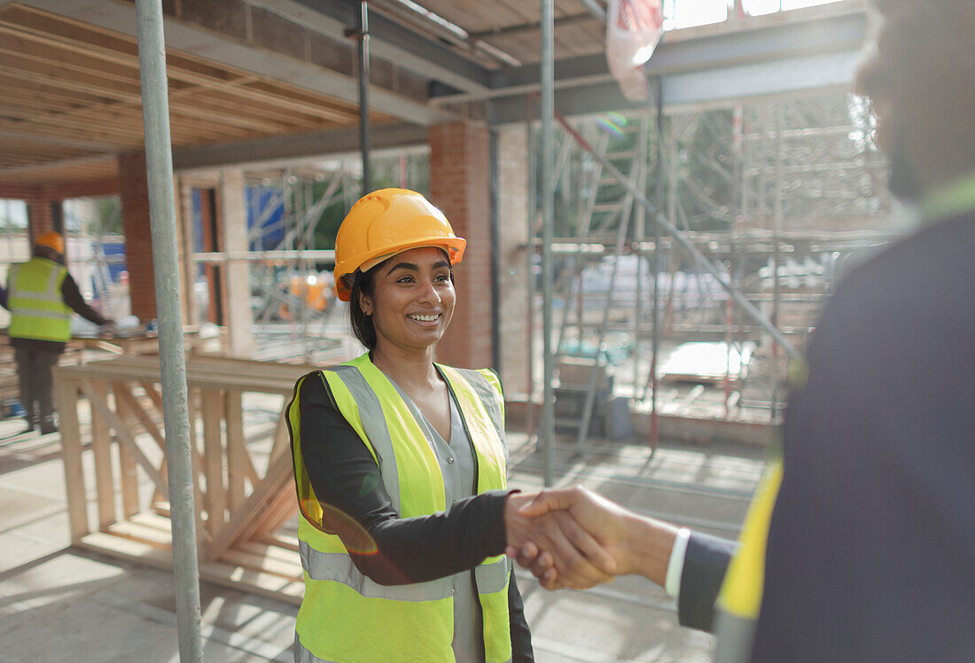 Architect and forewoman shaking hands at construction site