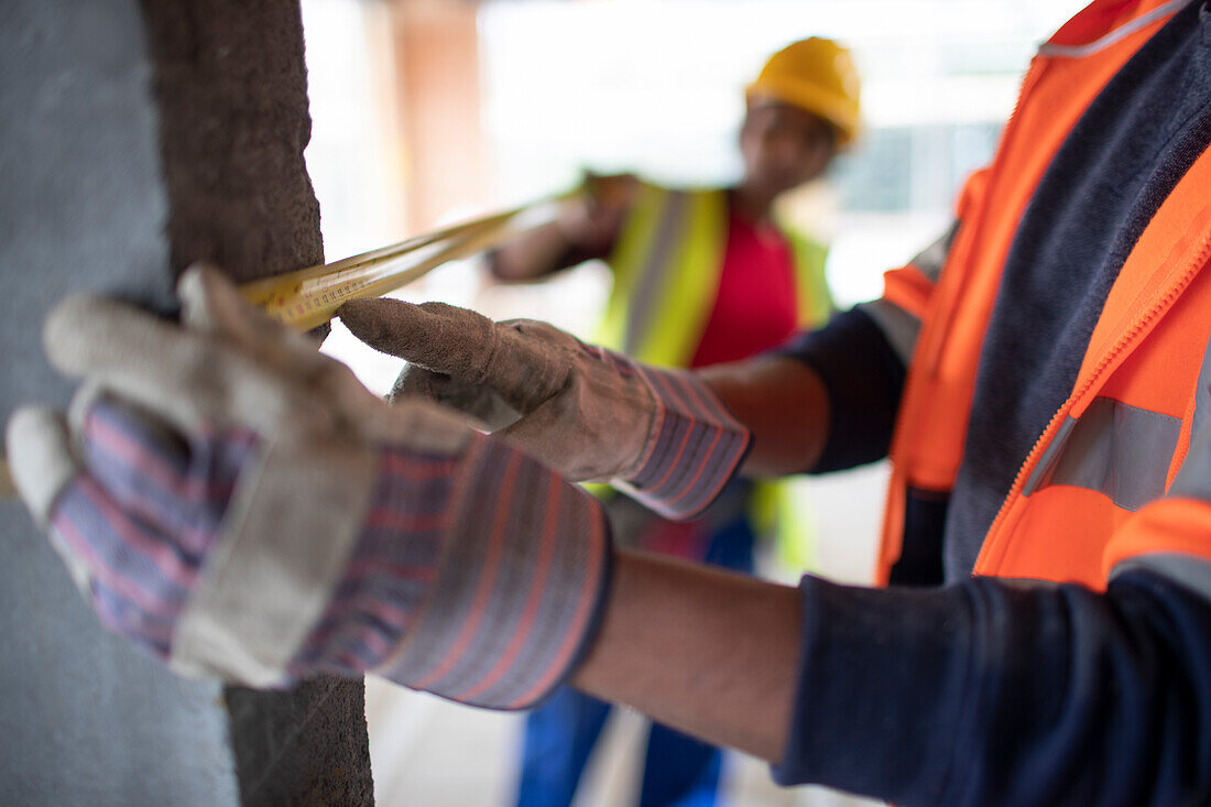 Construction workers using tape measure