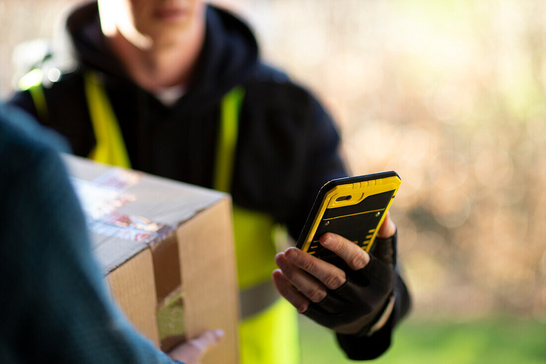 Courier with smartphone delivering package