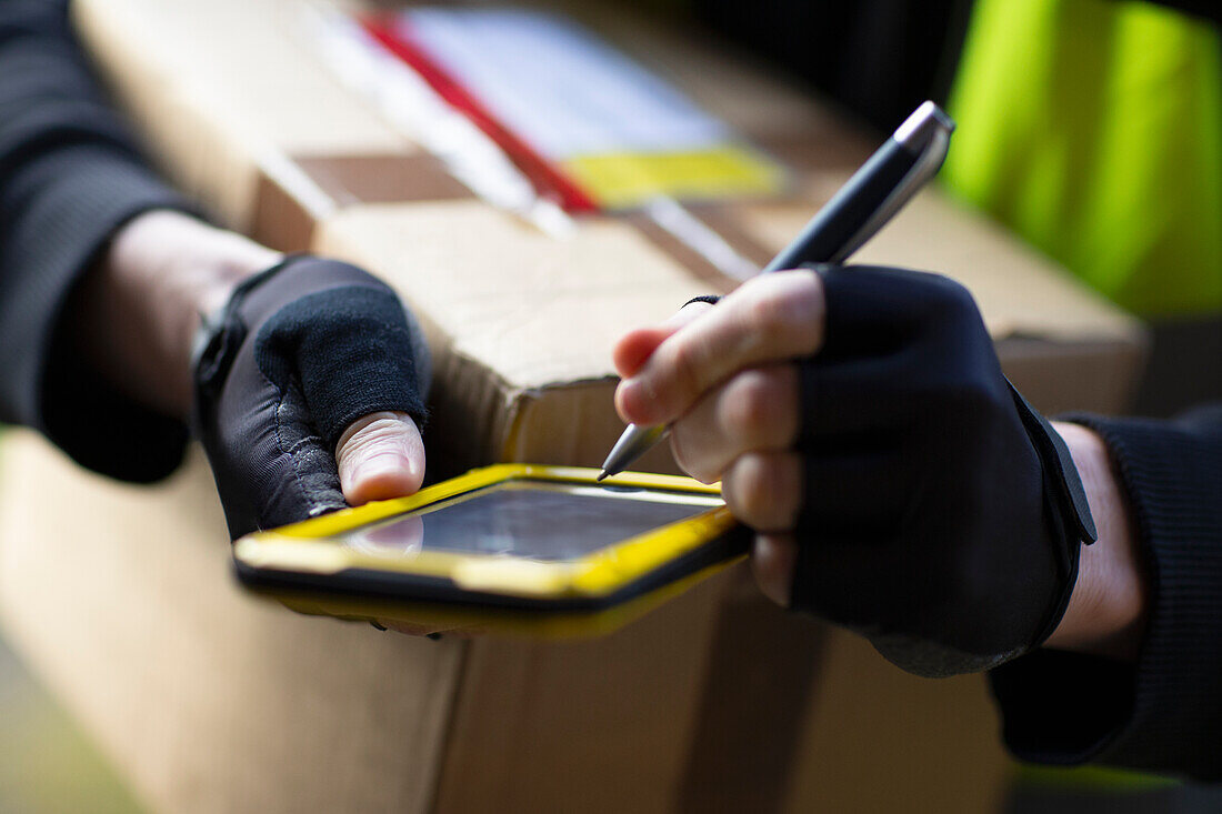 Courier with smartphone and stylus delivering package