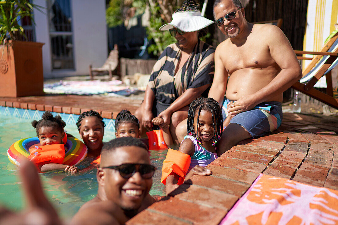 Happy multigenerational family at sunny summer swimming pool