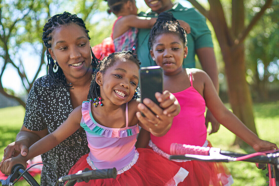 Happy mother and daughters taking selfie in park