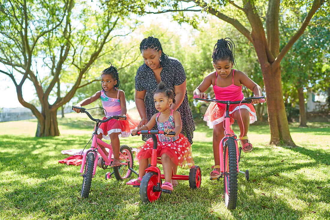 Mother and daughters with bicycles and tricycle in park