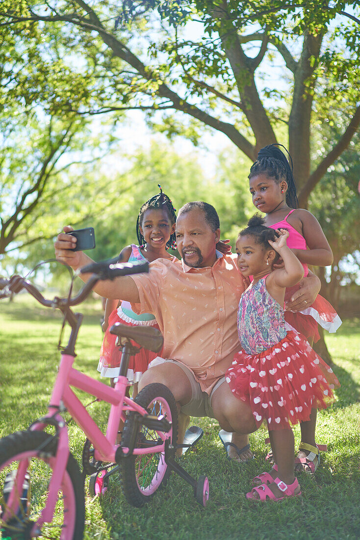 Grandfather and granddaughters taking selfie in park