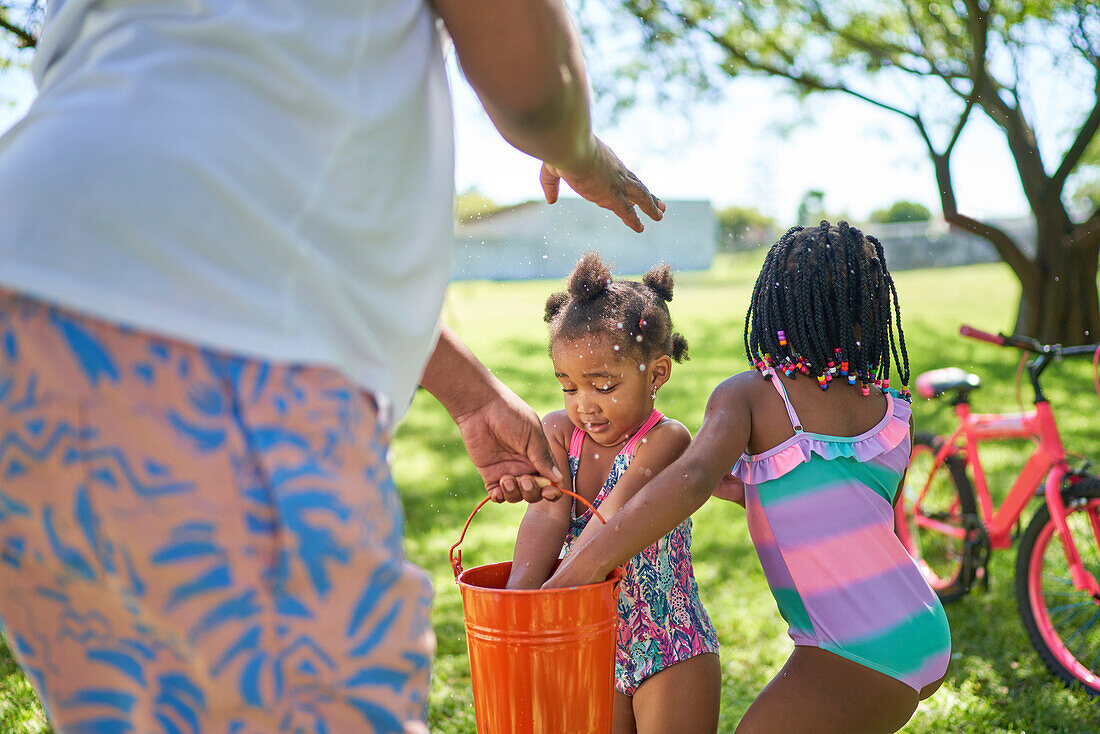 Father and daughters splashing water in backyard