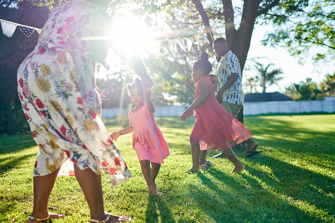 Family dancing in sunny backyard