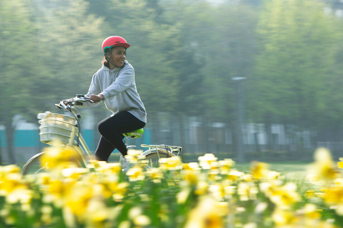 Happy young woman riding bicycle in sunny park