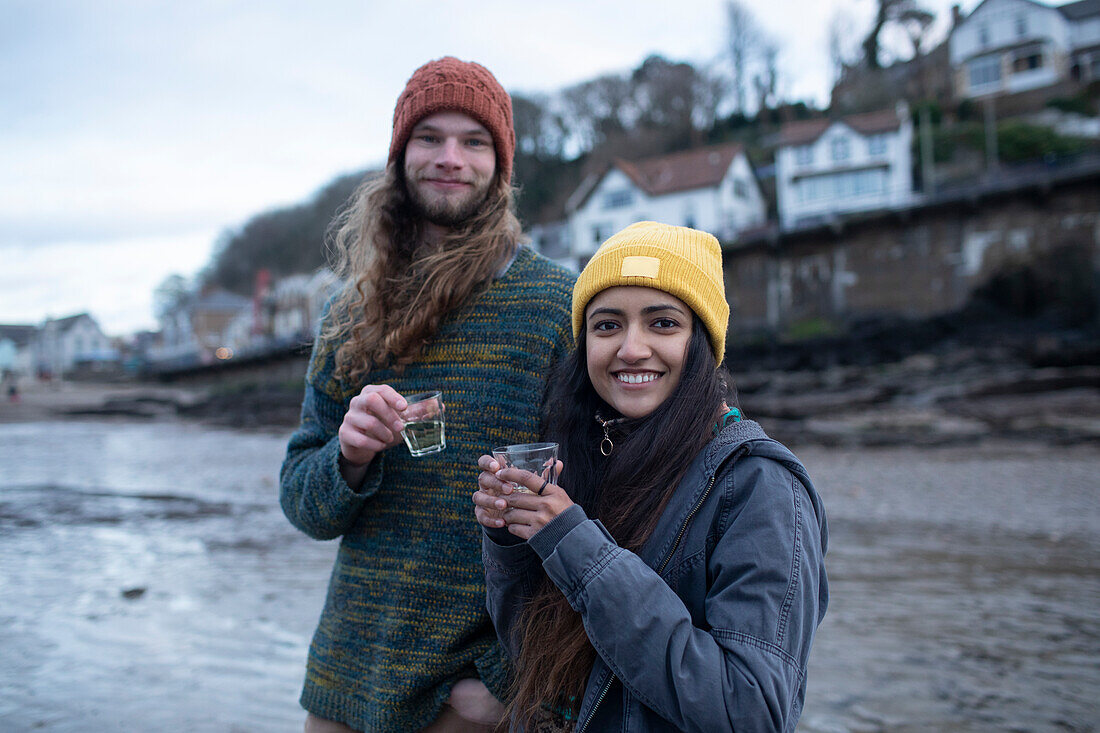 Happy young couple drinking on cold beach