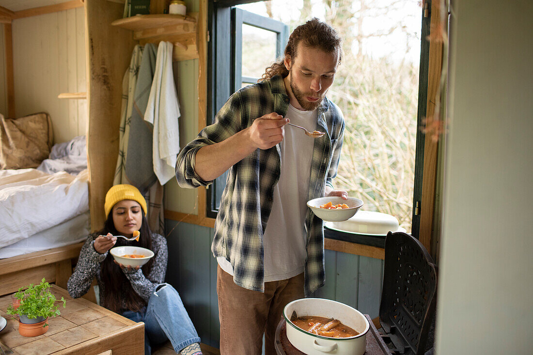 Young couple cooking in tiny cabin rental