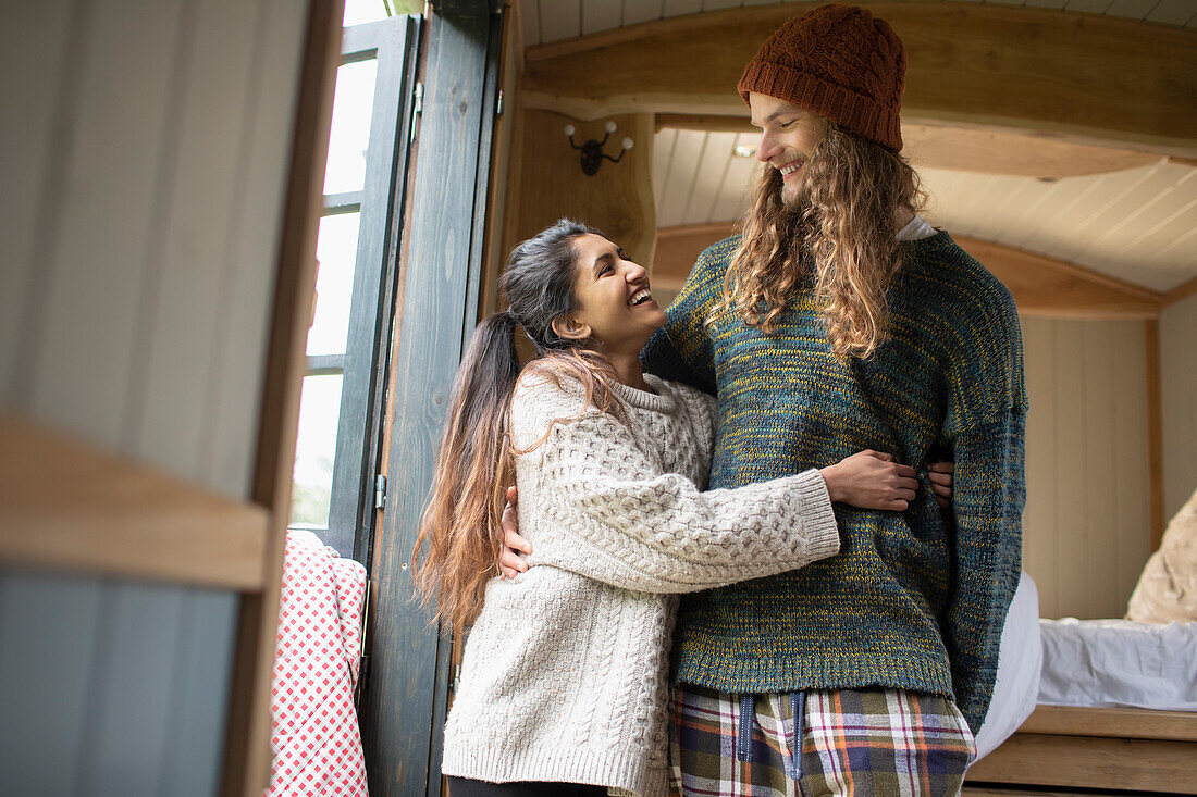 Happy young couple hugging in tiny cabin rental