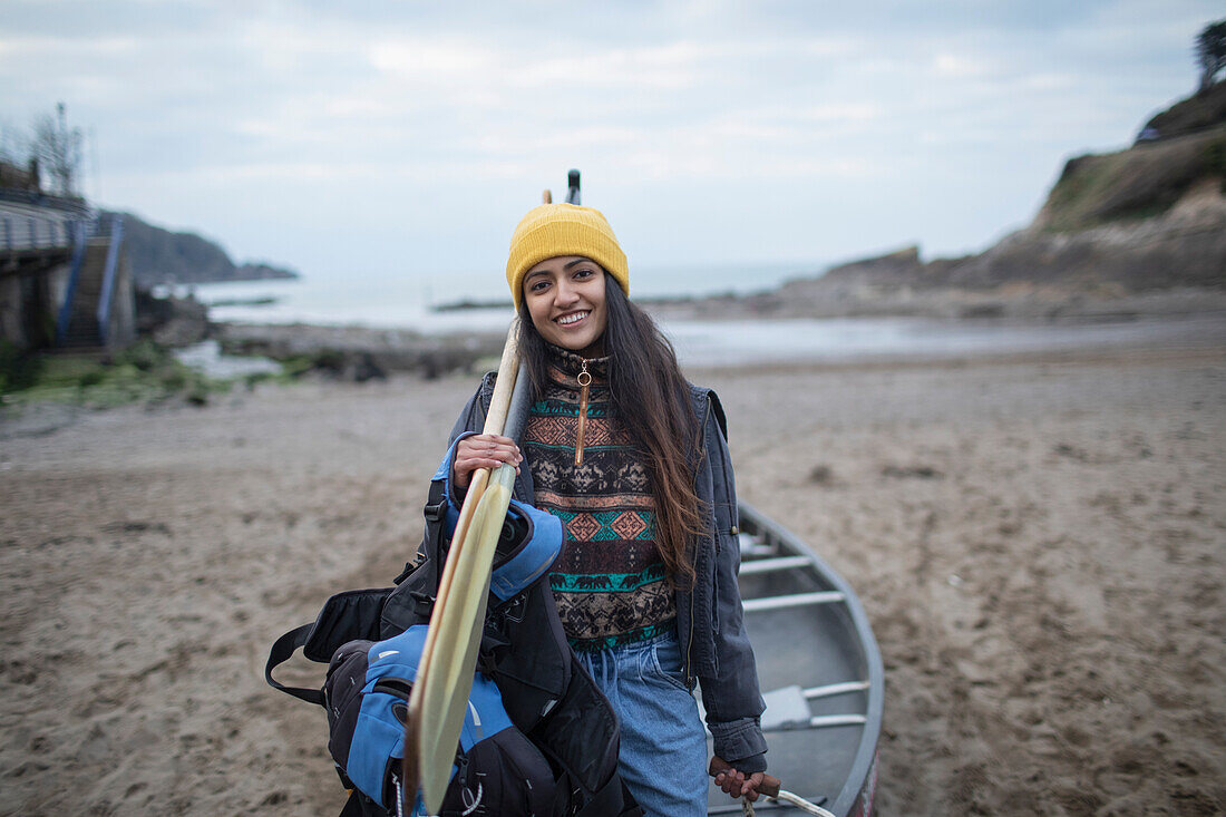 Happy young woman with canoe and oars on beach