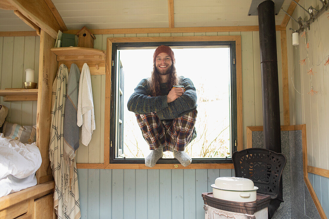 Happy young man in pyjamas in tiny cabin window