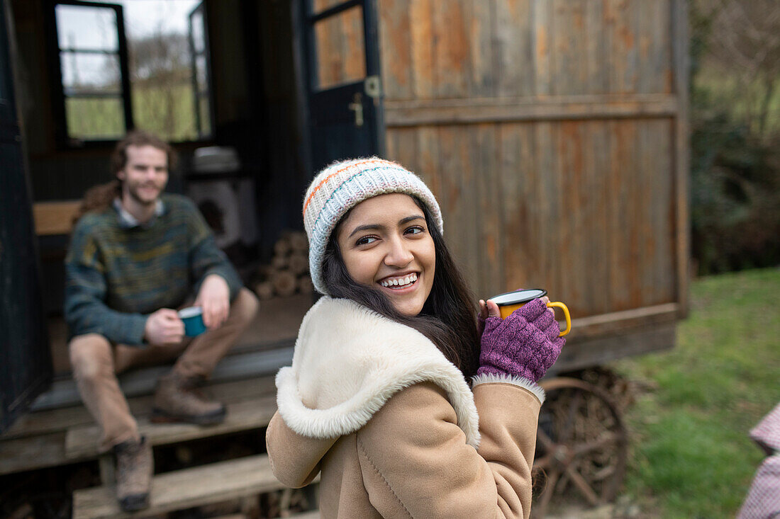 Happy young woman drinking coffee outside tiny cabin rental