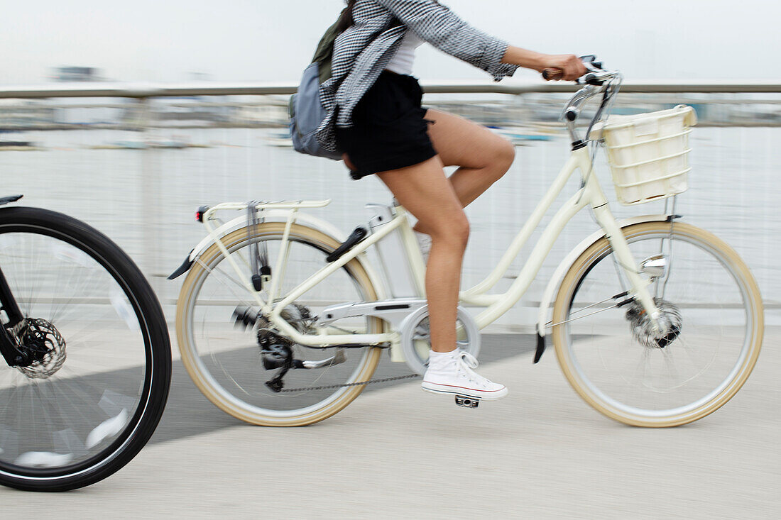 Young woman riding bicycle on bridge