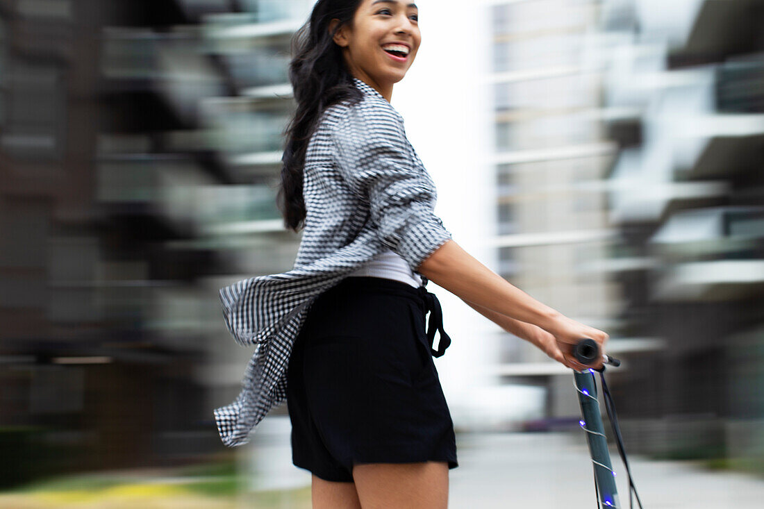 Carefree teenage girl riding scooter in city