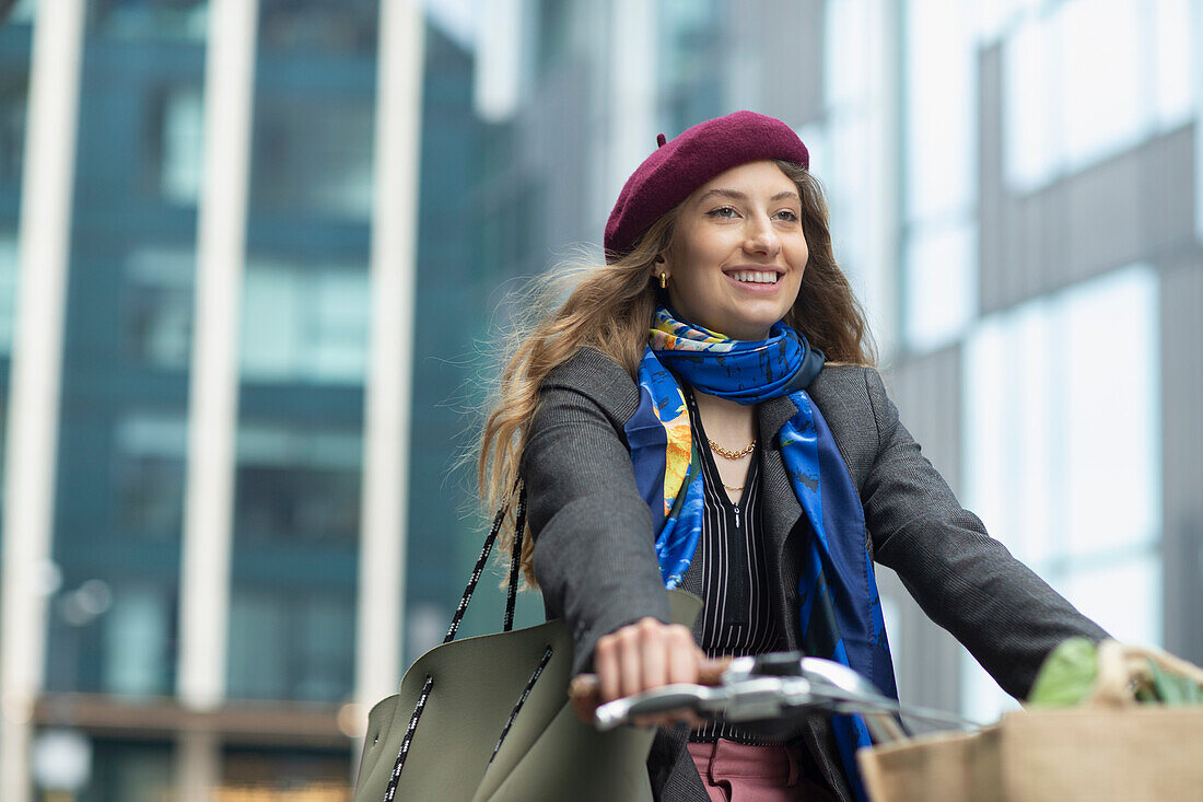 Happy young woman in beret riding bicycle
