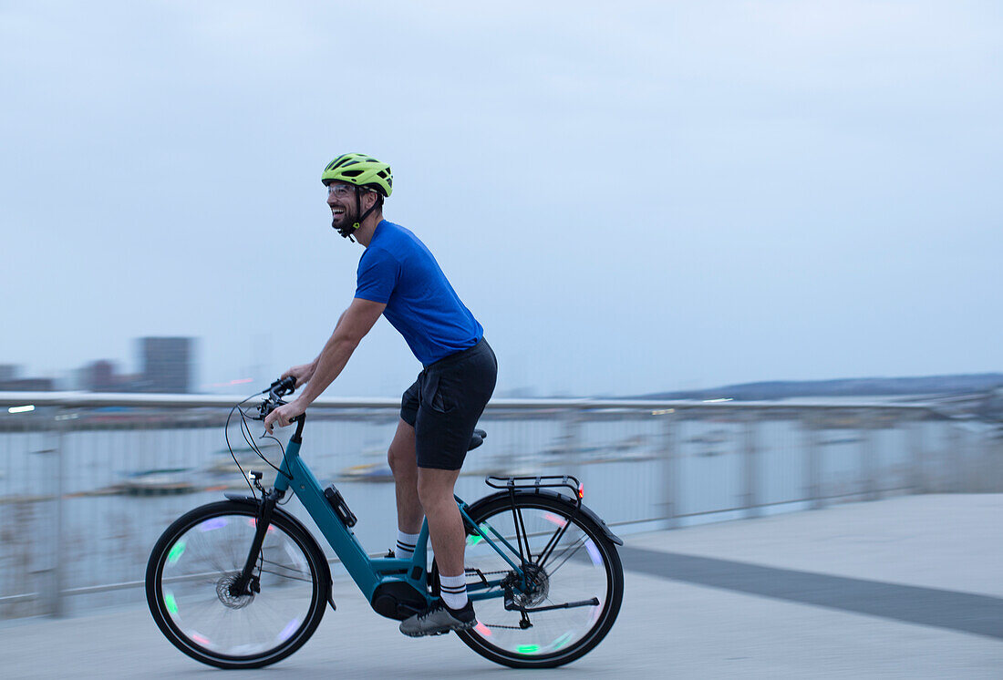 Man riding bicycle along urban waterfront