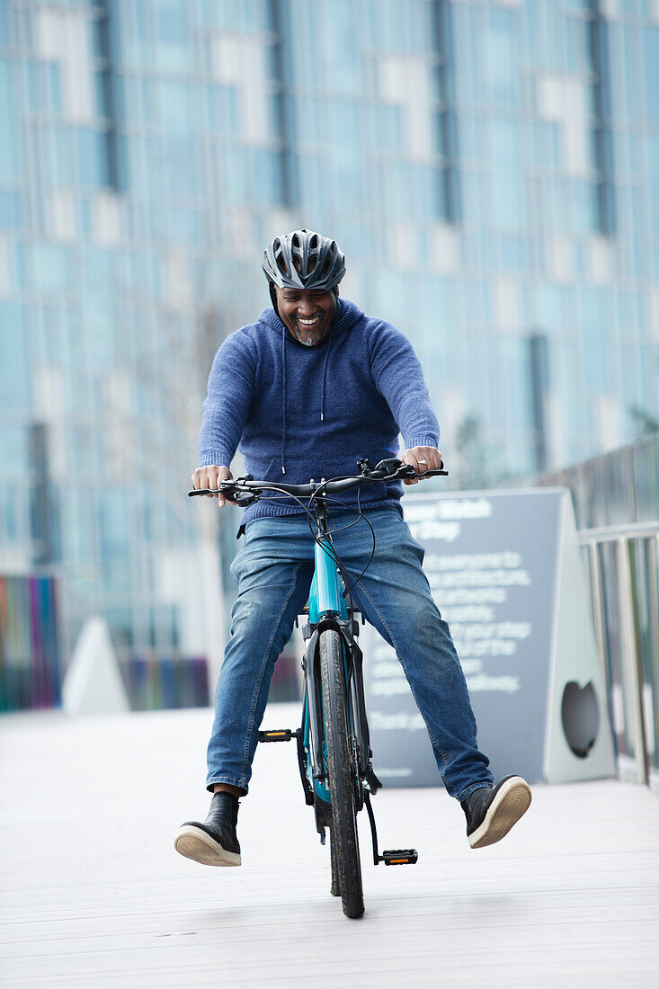 Happy man riding bicycle on urban sidewalk
