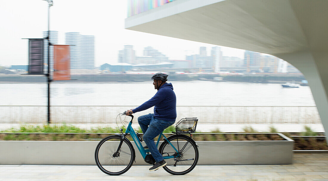 Man riding bicycle along city waterfront