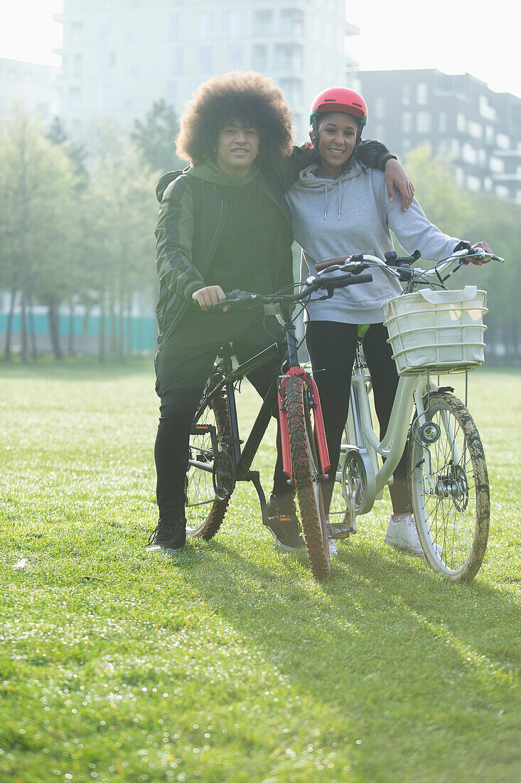Happy teen couple on bicycles in urban park