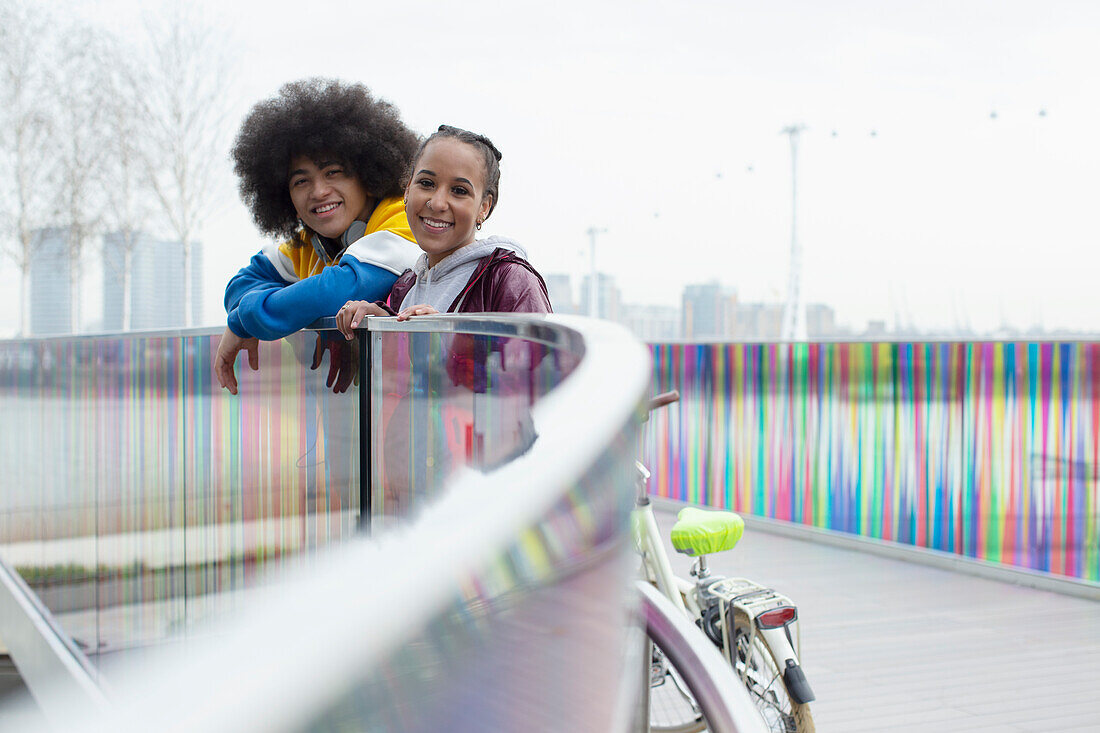 Happy twin brother and sister on modern footbridge