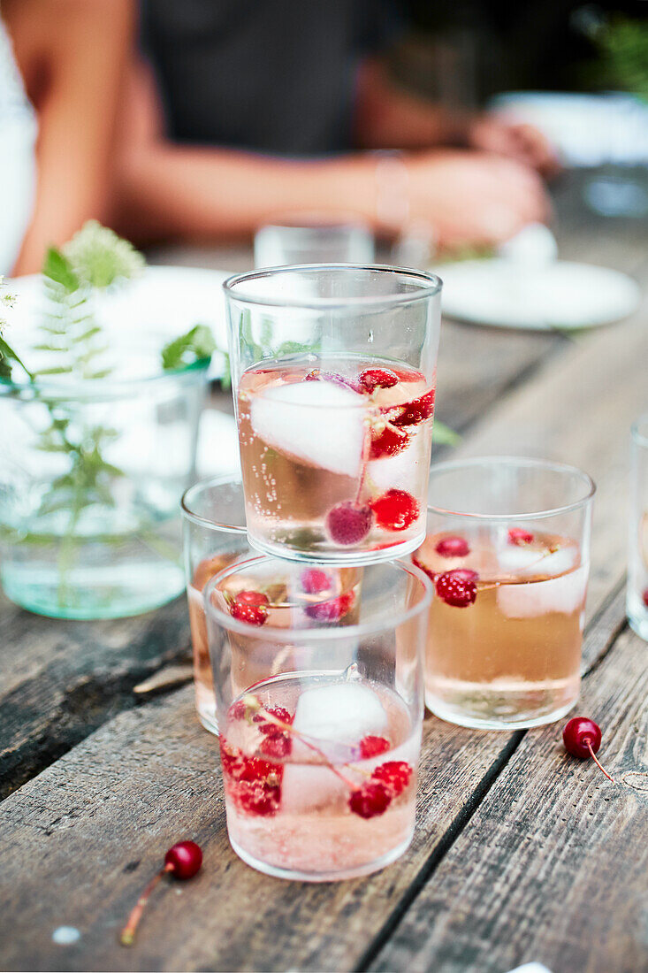 Mehrere Gläser Spritzer mit Rosé-Wein und Wodka auf Tisch im Garten