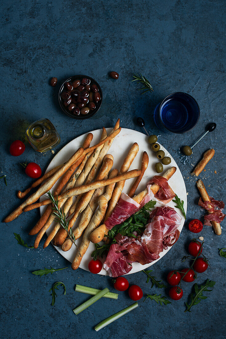 Parma ham and rosemary breadsticks with olives and tomatoes