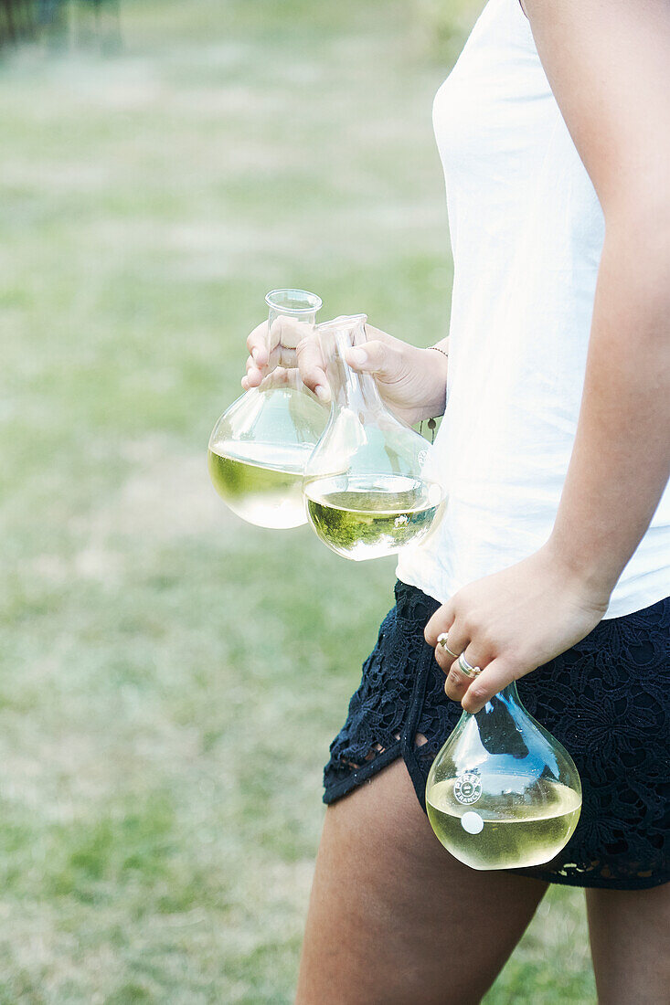 Woman carrying three white wine carafes