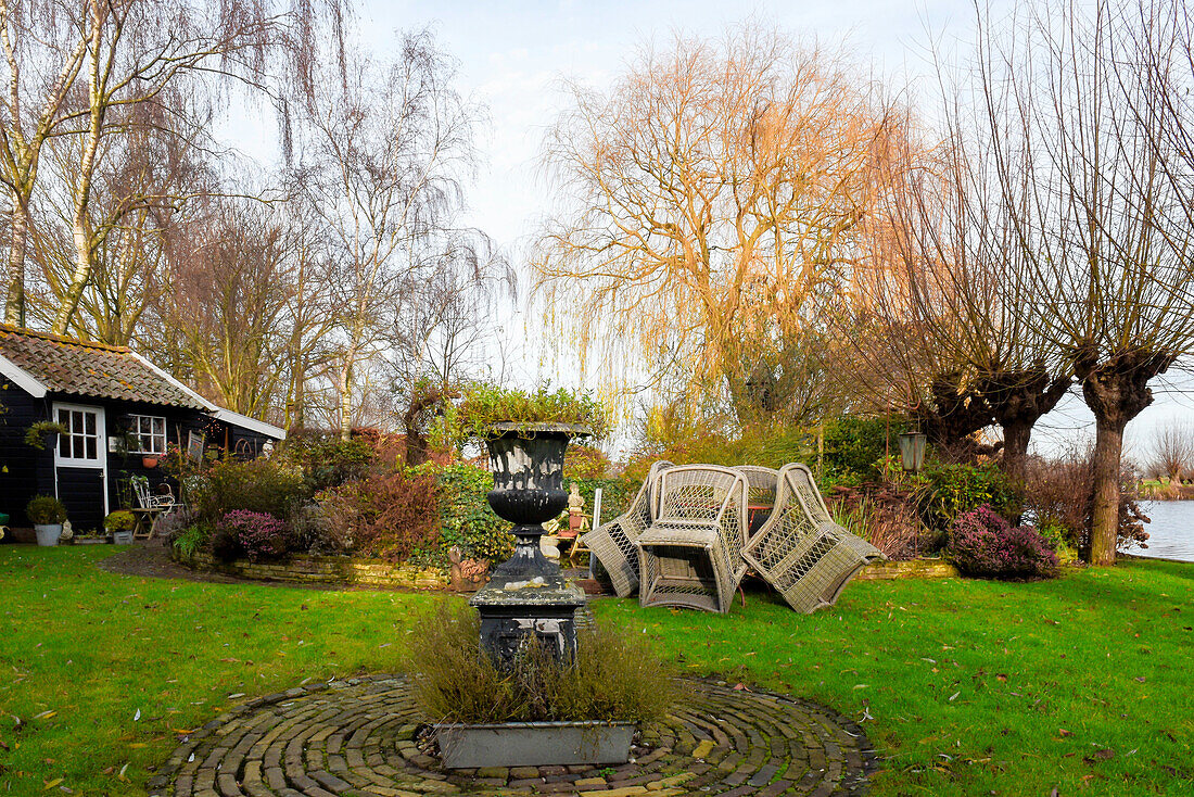 Urn in autumnal garden with summerhouse by a lake