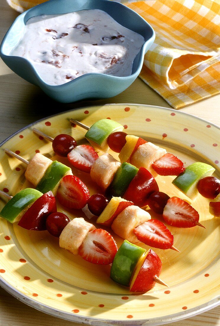 Colourful fruit kebabs on plate & a bowl of fruit quark