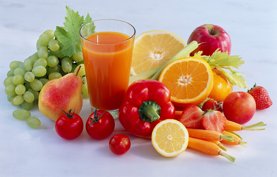 Glass of fruit and vegetable juice, surrounded by fruit and vegetables