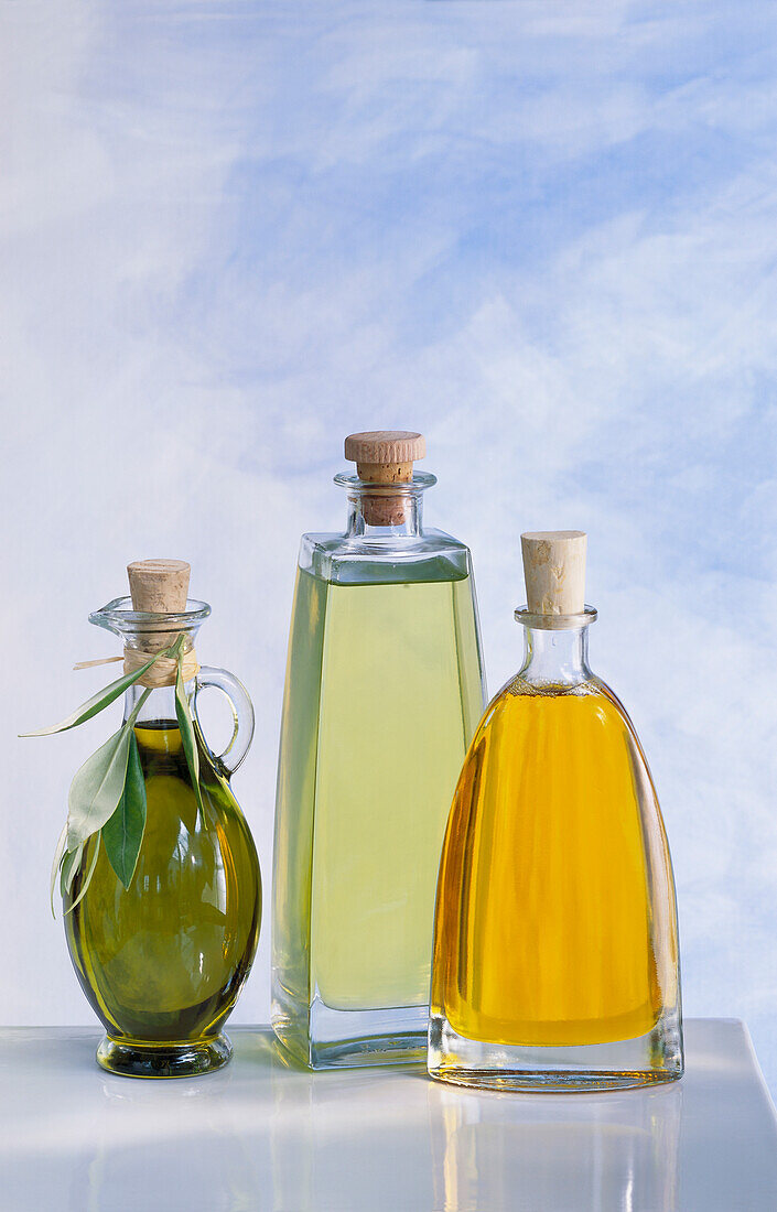 Three bottles of oil: olive oil, grape seed oil and linseed oil