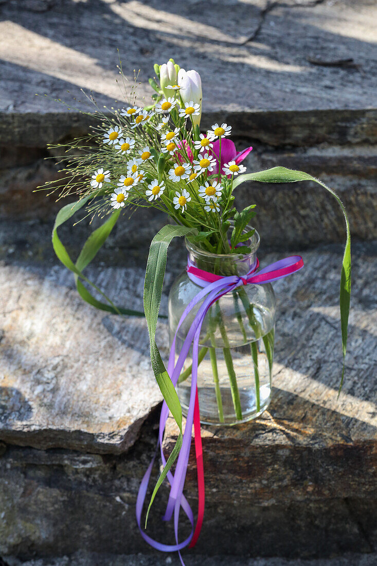 Bouquet of chamomile flowers and freesias in glass vase