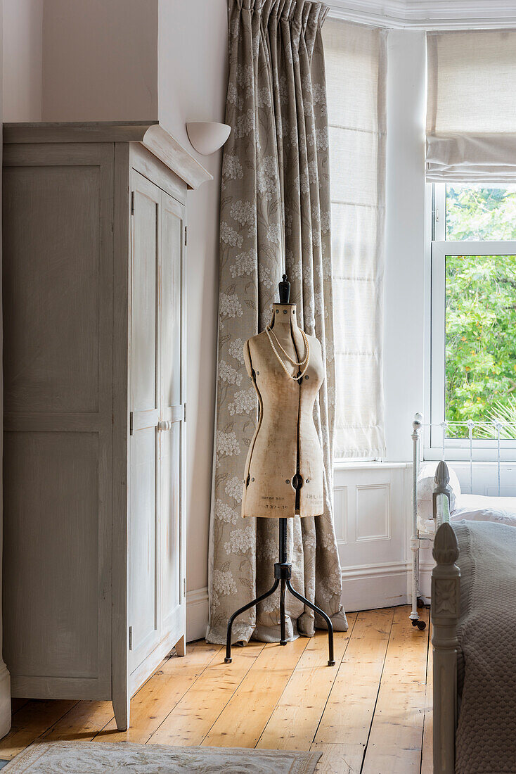 Vintage-style dressmaker's dummy next to grey wardrobe