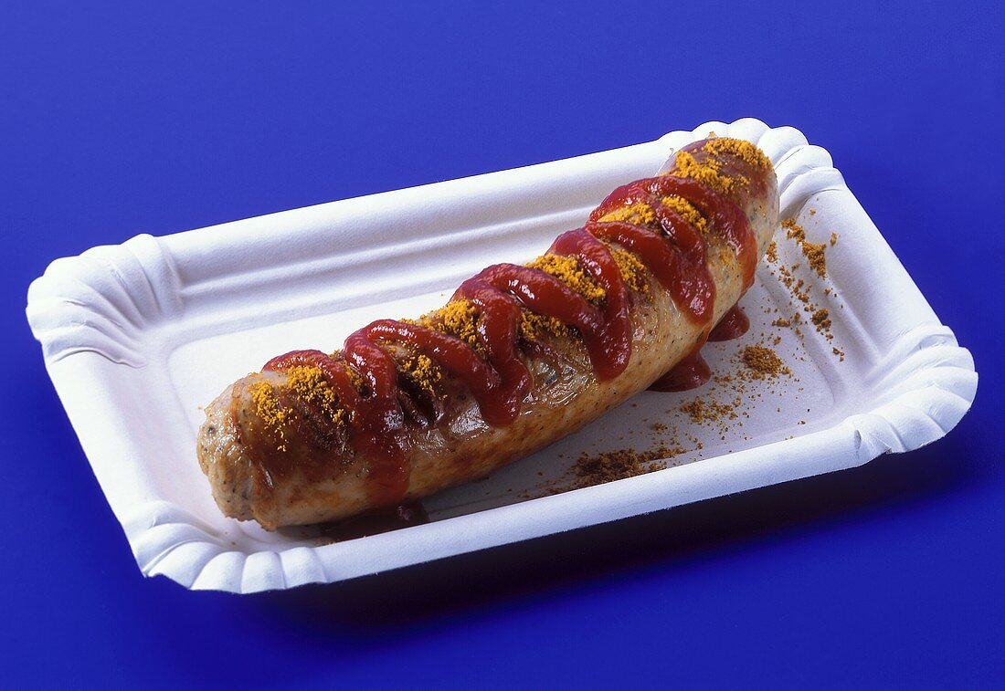 A curry sausage on paper plate
