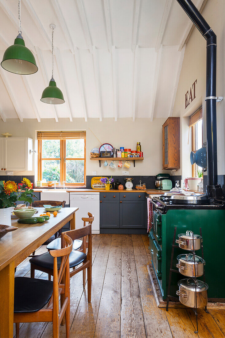 Küche im Landhausstil mit grünem Herd, Essbereich und Pendelleuchten