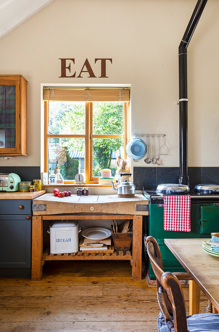 Landhausküche mit Holztheke und "EAT"-Schriftzug über dem Fenster