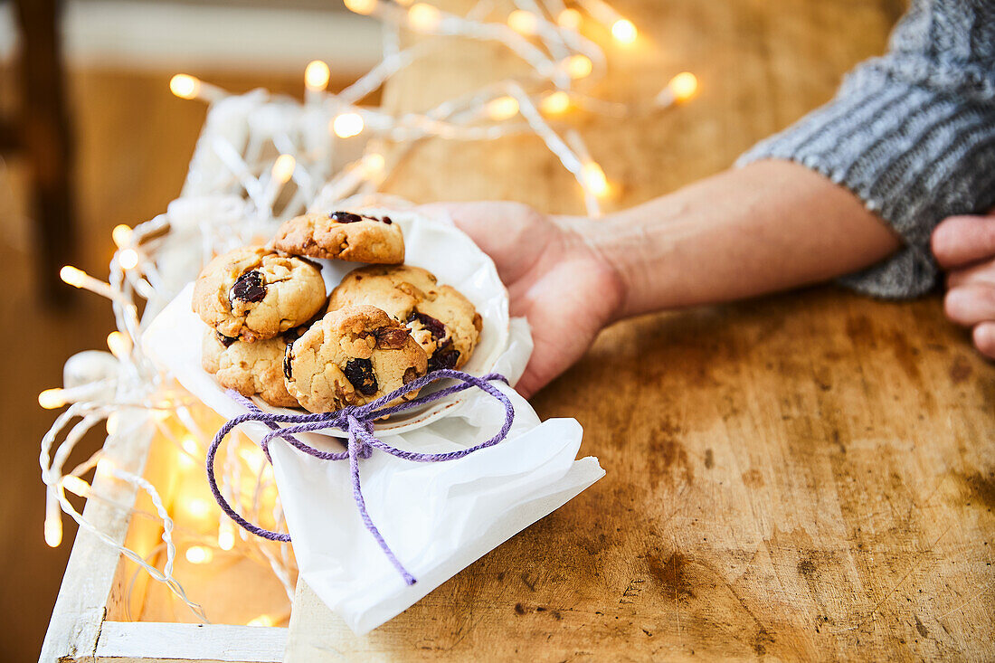 Hand hält Teller mit Cranberry-Cookies