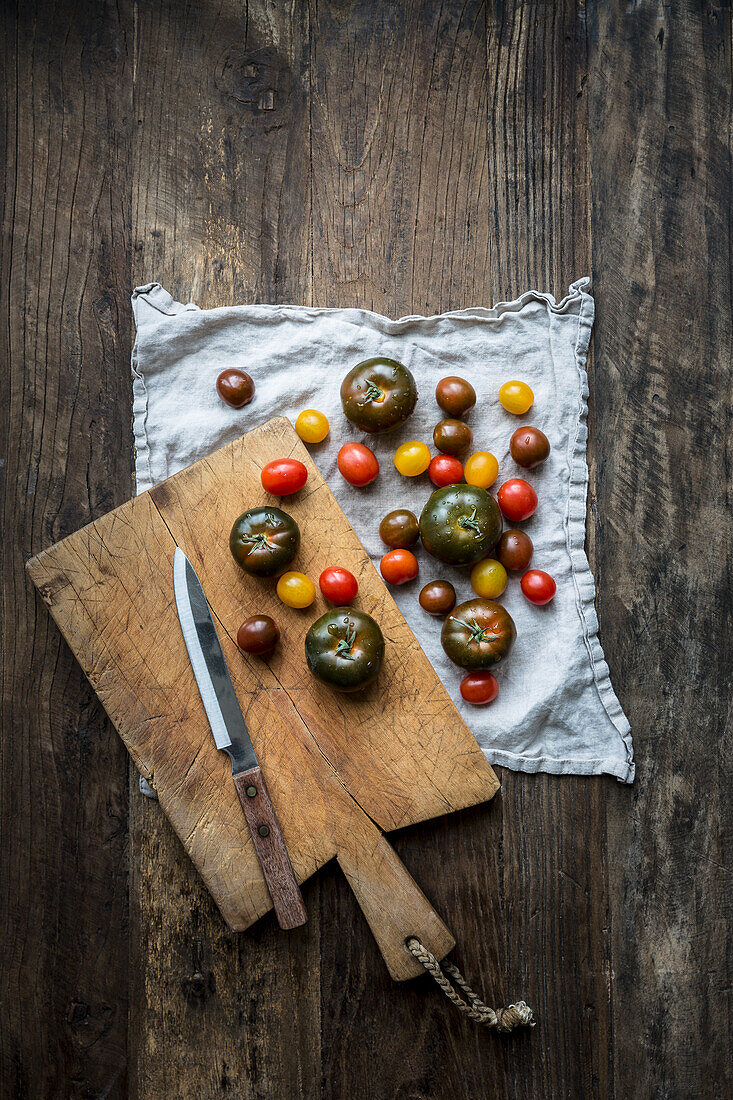 Mixed varieties of washed tomatoes on a linen tea-towel with chopping board