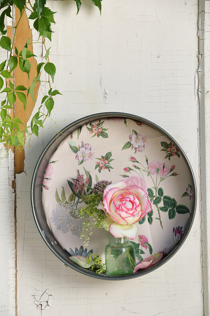 Kleine Vase mit 'Eden Rose' in alter Springform mit Blumentapete