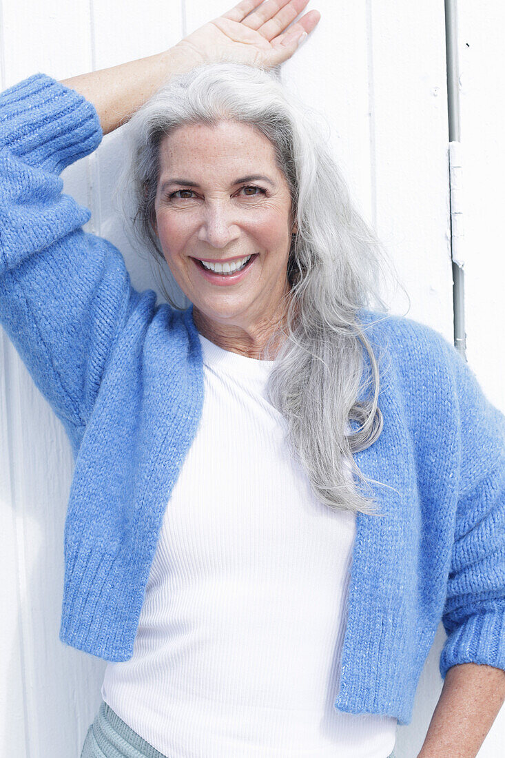 Mature woman with grey hair in white t-shirt and blue cardigan