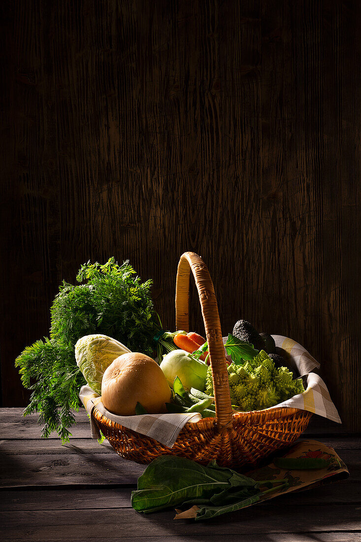 Korb mit frischen Karotten, Bohnen Chinakohl, Romanesco, Erbsenschoten, Kohlrabi und Avocado