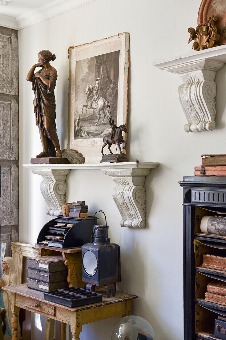 Schreibtisch mit Vintage Dekoration, darüber Regal mit Skulpturen